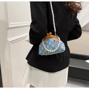 Detail of light blue denim purse with butterfly embroidery and pearl chain straps