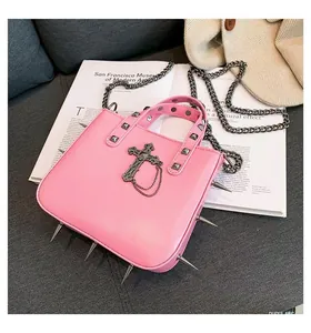 Detail of pink punk handbag with silver studs, cross pendant and metal chain strap