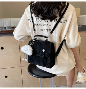 Detail of black pleated backpack with cloud charm shown on model in a home setting