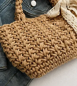 Detailed close-up of light brown handmade woven tote bag with a white lace bow accent