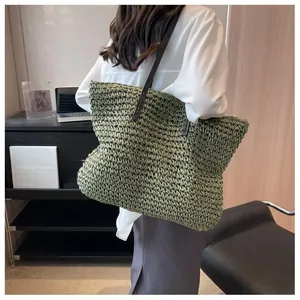 Detailed texture of green woven straw tote bag with slim dark brown leather shoulder straps