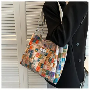 Detail of colorful patchwork tote bag featuring metal chain strap and niche design label