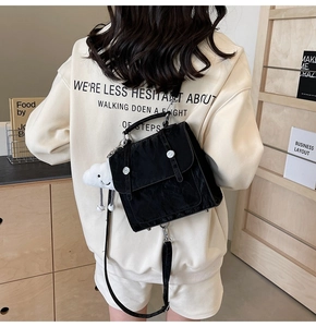 Detail of black glossy textured backpack featuring silver buckles and cute cloud charm