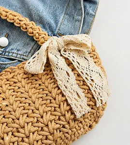 Detail of handmade woven bag featuring white lace bow and sturdy braided top handle