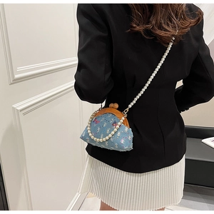 Detail of blue denim mini bag featuring purple butterfly embroidery and pearl chain strap