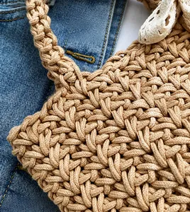 Detail of hand-woven straw bag texture featuring a soft white lace bow decoration