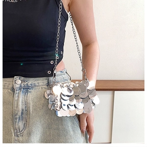 Close-up of silver sequin mini bag with metallic chain strap worn by a model