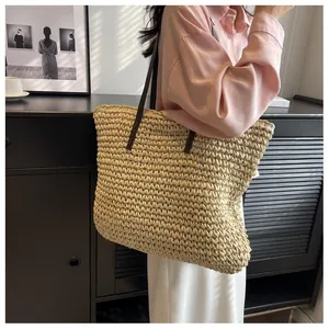 Detailed close-up of natural woven straw tote bag with brown leather shoulder straps