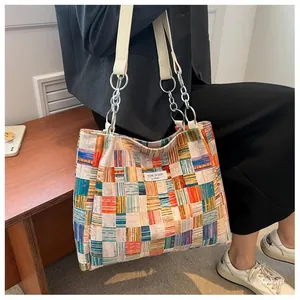 Detail of colorful woven tote bag featuring niche design label and metal chain shoulder strap