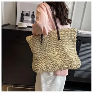Close-up of a large woven straw tote bag with brown straps worn on shoulder