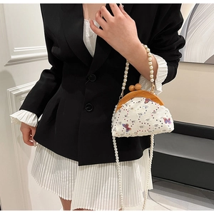 Detailed view of white sequined handbag with butterfly embroidery and pearl strap