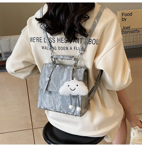 Detailed texture of grey pleated backpack with a plush cloud pendant for women