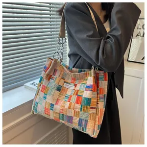 Detail of color-block woven tote bag with metal chain strap worn on model shoulder