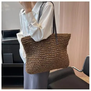 Close-up of a large brown straw tote bag with dual shoulder straps for casual beach style