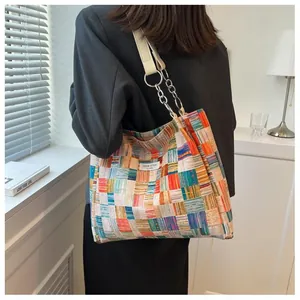 Detail of colorful patchwork tote bag with metal chain strap and leather handle design