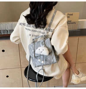 Close-up of a glossy grey backpack with pleated texture and white cloud plush charm