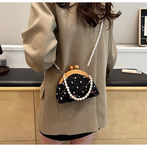 Detail of vintage black embroidered bag with wooden frame and white pearl chain strap