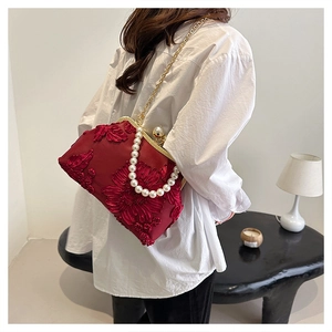 Détail de broderie florale rouge sur sac coquille vintage avec anse en perles et chaîne