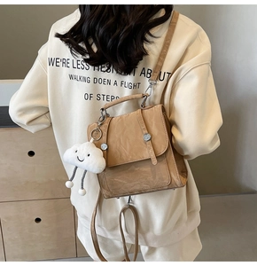 Detail of camel backpack with pleated texture and plush cloud charm on a model