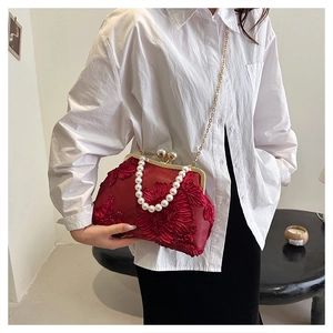 Détail du sac coquille en satin rouge avec broderie florale et anse en perles blanches