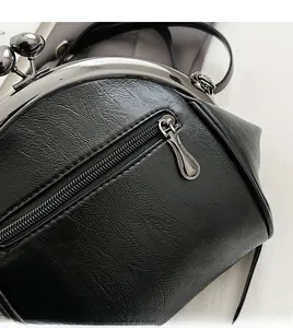 Close-up of black litchi pattern PU leather bag with smooth metal zipper and kiss-lock