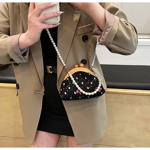 Detail of vintage crossbody bag with butterfly embroidery and elegant pearl chain strap