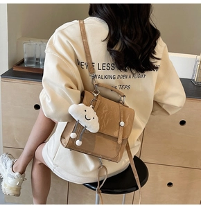 Detail of camel wrinkled texture backpack with a white cloud plush pendant accessory