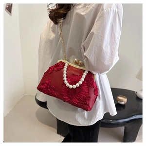 Détail du sac coquille rouge brodé avec fleurs, poignée en perles et fine chaîne dorée