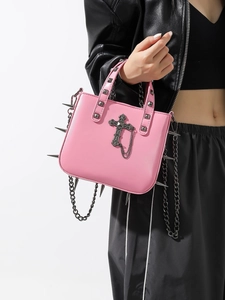Pink gothic punk handbag with metal spikes and cross pendant on a model