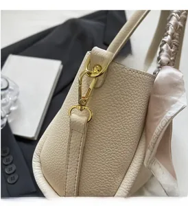 Close-up of litchi texture leather handbag with gold hardware and fashion silk scarf