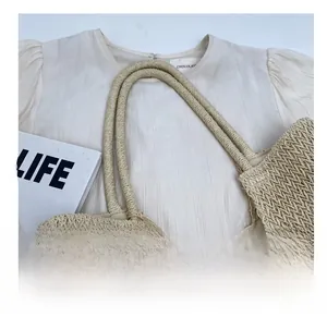 Detail of beige straw tote bag with tight cross-weave texture and brown bead accents