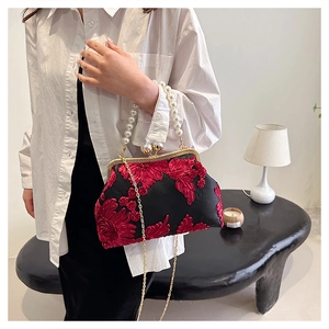 Détail d'un sac de soirée vintage avec broderies florales rouges et poignée en perles
