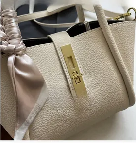 Close-up of litchi pattern leather bag with golden twist lock and fashion silk scarf