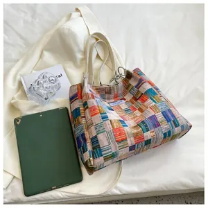 Detail of colorful plaid woven tote bag featuring Niche Design label and white handles