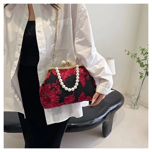 Détail d'un sac coquillage vintage noir avec broderies rouges et anse perle