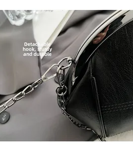 Detail of black pebbled leather shell bag featuring detachable silver metal rings and chain