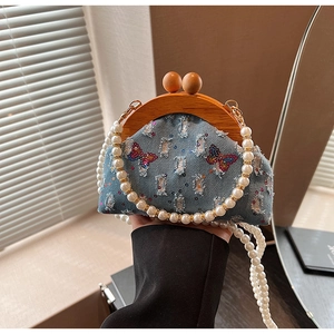Detail of blue denim bag with butterfly embroidery and pearl strap texture
