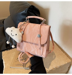 Close-up of pink textured handbag with silver buckles and a white cloud charm accessory