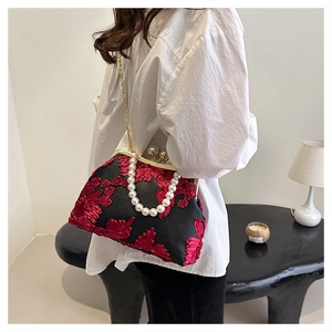Détail de broderie florale rouge sur sac coquille vintage avec perles et chaîne d'or