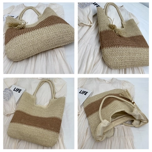 Detail view of large striped straw tote bag showing fringe tassel and woven rope handles