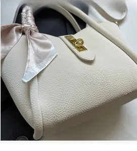 Macro shot of lychee grain cream bucket bag with gold twist lock and fashion silk scarf