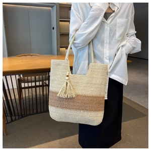 Detail of striped woven straw tote bag featuring brown fringes and spacious interior