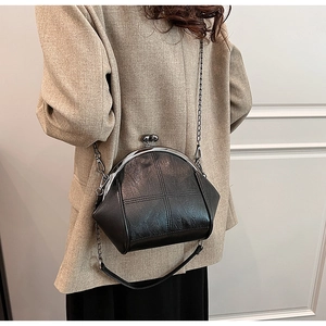 Detail of vintage black kiss-lock shell bag with cross stitching and metal chain