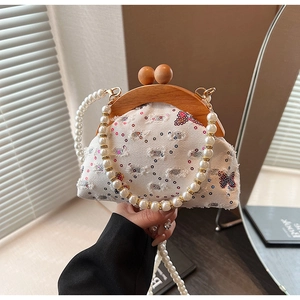 Detail of white sequined evening bag with butterfly embroidery and wooden clasp