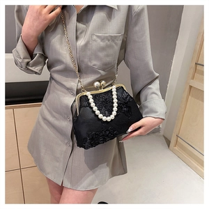 Détail du sac coquillage en dentelle noire avec poignée en perles et fermoir doré vintage