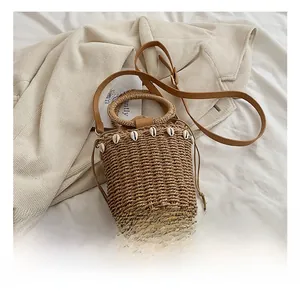 Detail shot of straw bucket bag with shell ornaments and drawstring lining on beige blazer
