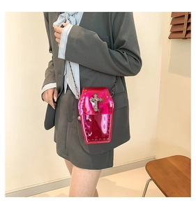 Detail of coffin-shaped cross crossbody bag in magenta laser leather with silver metal chain