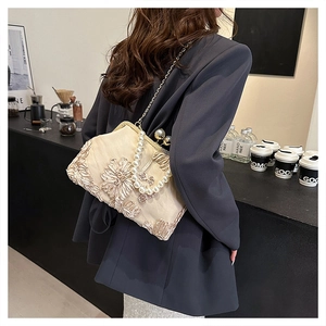 Détail du sac beige avec broderie florale, poignée en perles et bandoulière chaîne