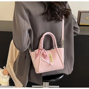 Détail du sac en cuir litchi rose avec poignée en foulard et boucles dorées