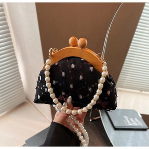 Detail of elegant black sequin evening bag with natural wood frame and pearl chain